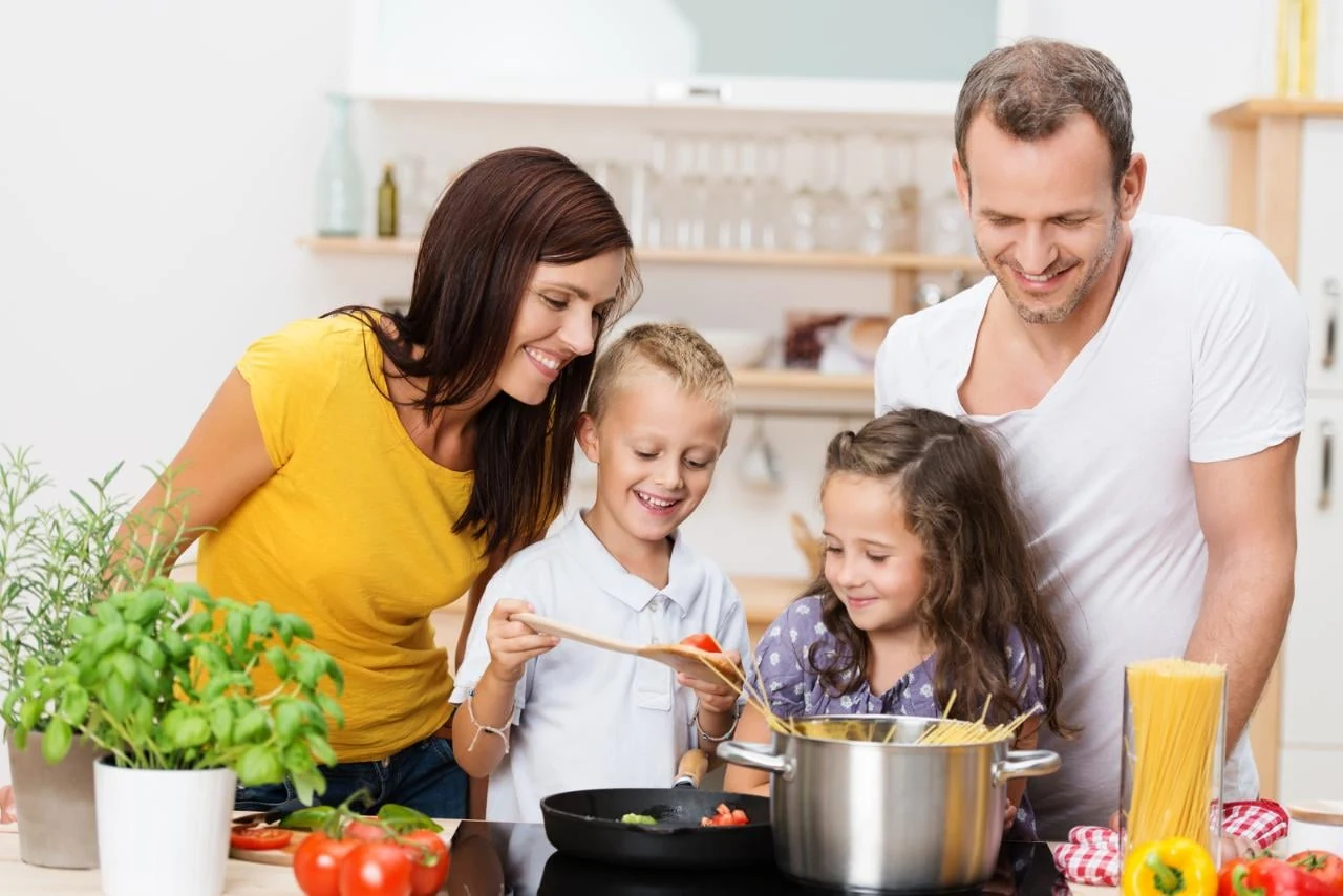 A family preparing food together in a kitchen with fresh herbs